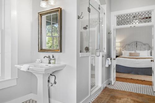 a white bathroom with a sink and a shower at Blacksmith Quarters in Fredericksburg