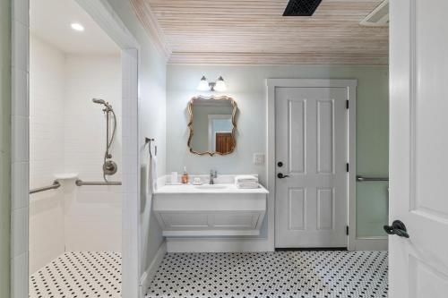 a white bathroom with a sink and a mirror at Blacksmith Quarters in Fredericksburg