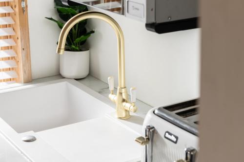 a kitchen sink with a gold faucet at Hazel - Connect to the Nature in the Hot tub in Blandford Forum