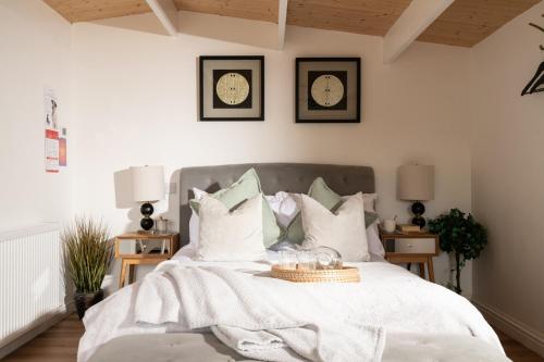 a bedroom with a white bed with clocks on the wall at Hazel - Connect to the Nature in the Hot tub in Blandford Forum