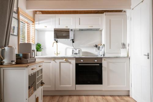 a kitchen with white cabinets and a black dishwasher at Hazel - Connect to the Nature in the Hot tub in Blandford Forum