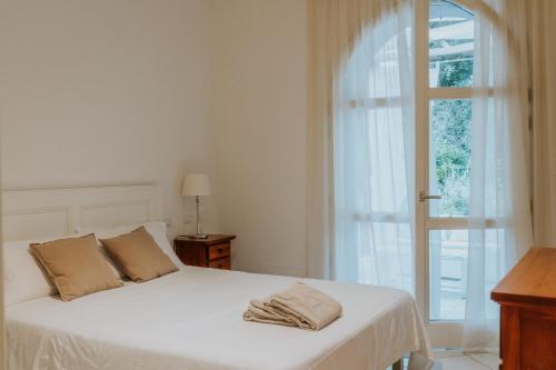 Cama blanca en habitación con ventana en Il Delfinetto, en San Vincenzo