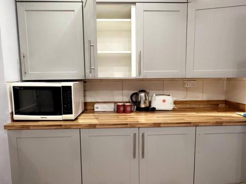 a kitchen with white cabinets and a microwave on a counter at Cosy Quiet Single Studio in Merton