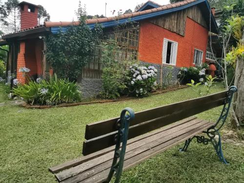 a wooden bench in front of a house at Chalé Mauá Conforto e Arte in Visconde De Maua