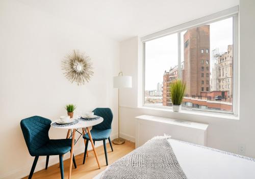 a white bedroom with a table and chairs and a window at Unique Studio Apartment At East Side in New York