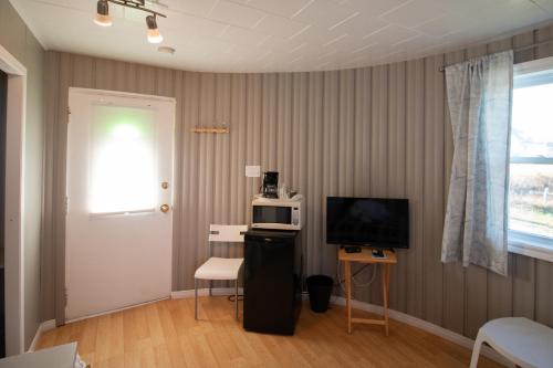 a living room with a television and a table with a microwave at Motel de la mer in Rimouski