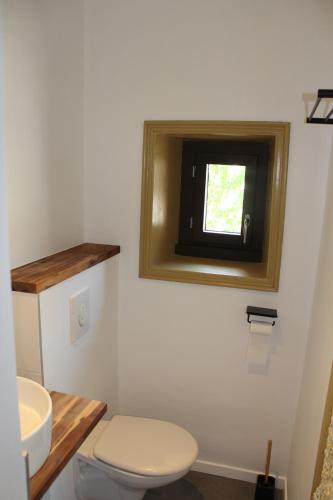 a bathroom with a toilet and a sink and a window at La Riveraine et les bicyclettes in Saint-Sauveur-de-Montagut