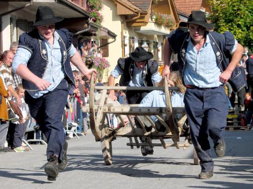 two men in cowboy hats pulling a cart in a parade at Chalet les Ecureuils Apartment Penthouse Suite in Crésuz