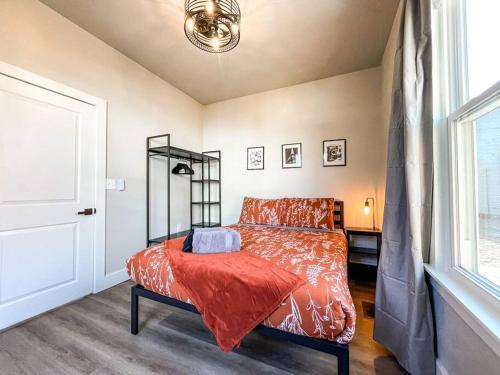 um quarto com uma cama com um edredão laranja e uma janela em Designer Retreat / Central loc/walk to brewery/café em Colorado Springs