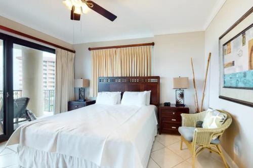a bedroom with a large white bed and a chair at Grand Pointe Unit 414 in Orange Beach