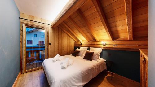 Un dormitorio con una cama grande con sábanas blancas. en Chalet Sétaz, en Valloire