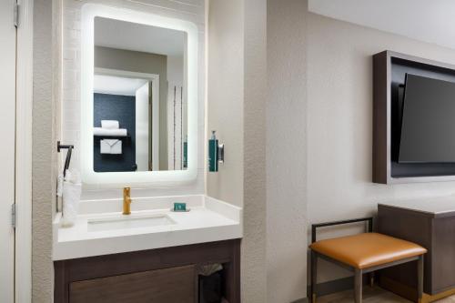 a bathroom with a sink and a mirror and a chair at DoubleTree by Hilton Charlotte City Center in Charlotte
