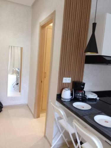 a kitchen with a counter top with two white chairs at Studio à Prestigia HayRiad/Rabat in Rabat