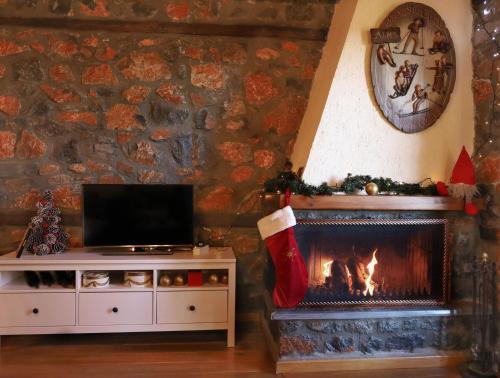 a living room with a fireplace and a tv at Παραδοσιακή μεζονέτα στον Π.Άγιο Αθανάσιο in Palaios Agios Athanasios