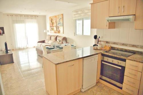 a kitchen with a stove top oven next to a living room at Apartamento Playa Xilxes in Xilxes