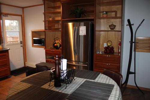 uma cozinha com uma mesa e um frigorífico de aço inoxidável em The Regis em Halifax