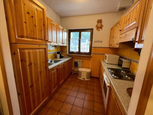 una pequeña cocina con armarios de madera y fregadero en A Casa Dei - Appartamento Colle Isarco, en Colle Isarco