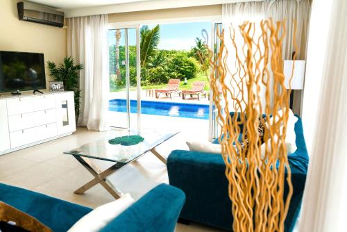 a living room with a blue couch and a glass table at Private Iberosta Villa Fortuna - 4BDR, Pool & Private Beach in Punta Cana