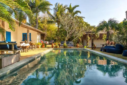 a swimming pool in the backyard of a house with palm trees at Awe Villa Boutique Trancoso in Trancoso
