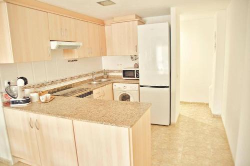 a kitchen with wooden cabinets and a white refrigerator at Apartamento Playa Xilxes in Xilxes