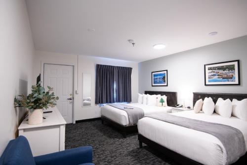 ein Hotelzimmer mit 2 Betten und einem blauen Stuhl in der Unterkunft Main Street Motel in Bar Harbor