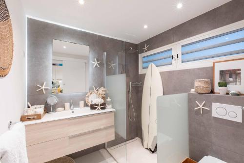 La salle de bains est pourvue d'un lavabo, d'un miroir et d'une planche de surf. dans l'établissement Art et mer suite Saint barth, à Anse des Cayes