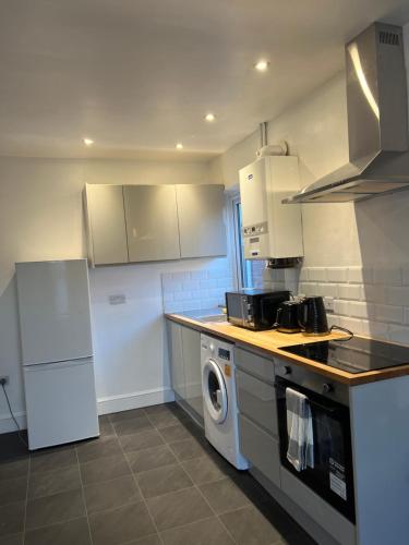 Modern 2 bed flat Southampton- Close to Central Station & Shops في ساوثهامبتون: مطبخ مع غسالة ملابس وغسالة