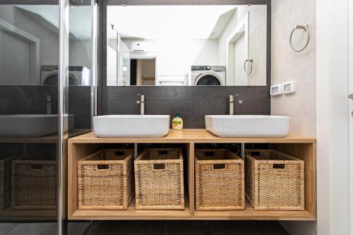 un bagno con due lavandini e cesti di vimini di Carmel Boutique Exclusive a Haifa