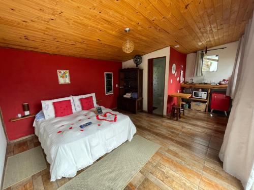a bedroom with a bed with a red wall at Chalé Madeira Rústica in Visconde De Maua