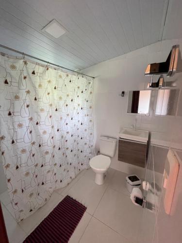 a bathroom with a toilet and a shower curtain at Chalé Madeira Rústica in Visconde De Maua