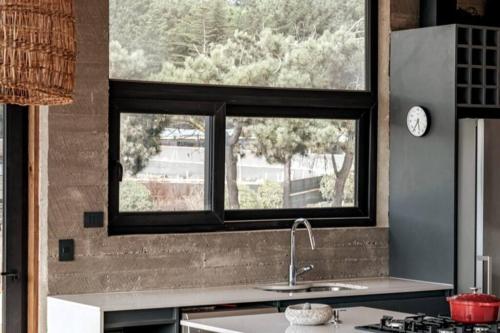 a kitchen with a large window above a sink at Punta Lobos Beachfront House, Taivarua in Pichilemu
