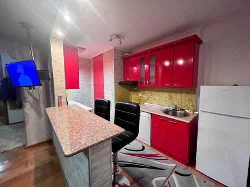 a kitchen with red cabinets and a sink and a refrigerator at MD Tuzla in Tuzla