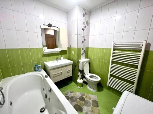 a green and white bathroom with a tub and a toilet at MD Tuzla in Tuzla