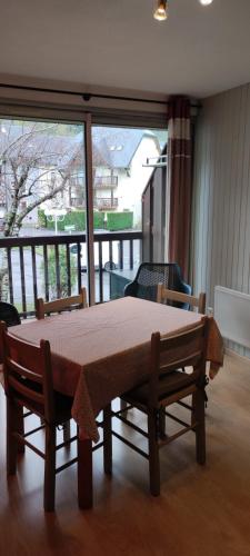 a table and chairs in a room with a balcony at Bel appartement Résidence Hameau du Parc Saint Lary Vignec in Vignec