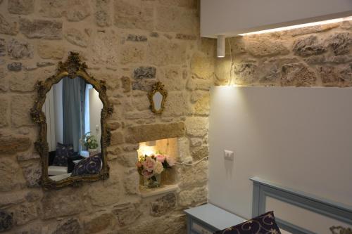 a room with a stone wall with a mirror at DIMORA DEL CARMINE in Bari