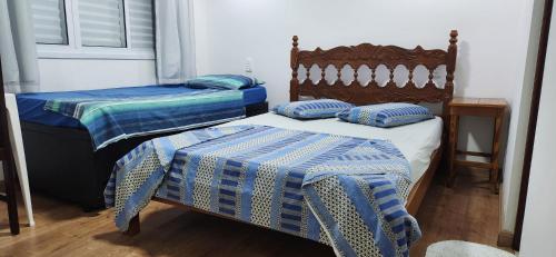 twee bedden met blauwe en witte dekens en kussens bij Residence Maria Andrade in Águas de Lindóia