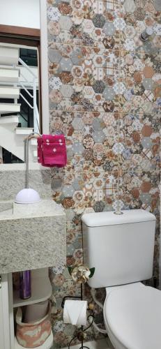 een badkamer met een toilet en een tegelwand bij Residence Maria Andrade in Águas de Lindóia