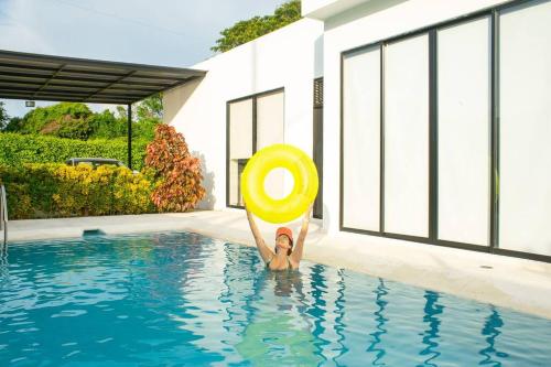 a person holding a yellow frisbee in a swimming pool at La Veranera in Girardot