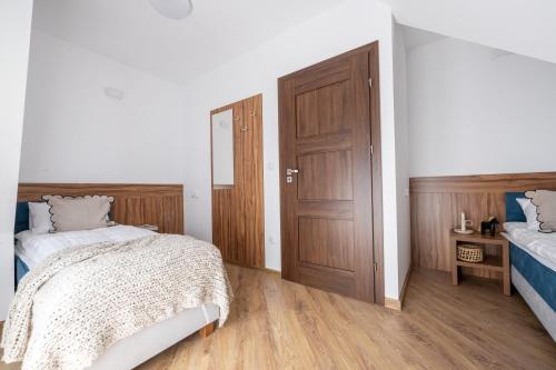 a bedroom with two beds and a wooden door at Para Apartments - Dwupoziomowe Apartamenty in Biały Dunajec