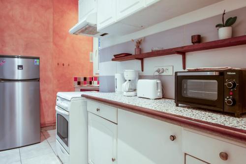 une cuisine avec des armoires blanches et un micro-ondes dans l'établissement Appartement Mercado - Châtelet - Welkeys, à Paris