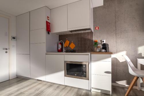 a kitchen with white cabinets and a microwave at Felicidade Aveiro Apartment incl Parking by Home Sweet Home Aveiro in Aveiro