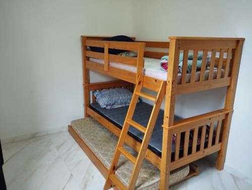 ein Etagenbett aus Holz mit einer Leiter in einem Zimmer in der Unterkunft LOCAMAR in Itanhaém