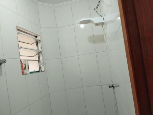 ein Bad mit einer Dusche und einer weiß gefliesten Wand in der Unterkunft LOCAMAR in Itanhaém