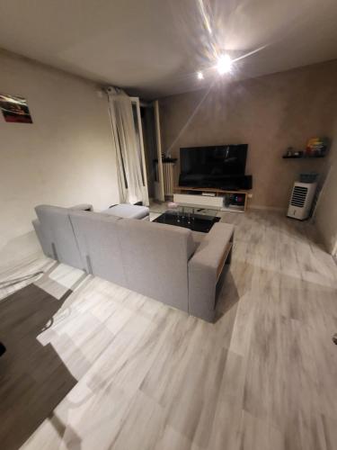 a living room with a couch and a television at Chambre Neuve dans un logement partagé in Allonnes