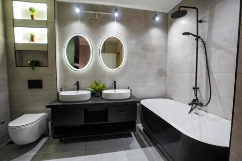 een badkamer met 2 wastafels, een bad en een spiegel bij Spacious flat 7 mins to Airport in Caïro