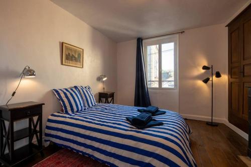 - une chambre avec un lit rayé bleu et blanc et une fenêtre dans l'établissement Maison du pêcheur 1 / Duplex chaleureux, à Argenton-sur-Creuse