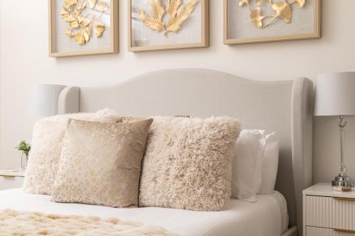 a bedroom with a white bed with pillows and pictures on the wall at Primrose - Holiday Cottage with Private Vineyard in Blandford Forum