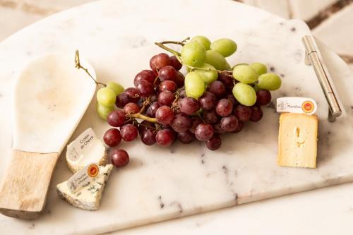 a bunch of grapes and cheese on a cutting board at Primrose - Holiday Cottage with Private Vineyard in Blandford Forum