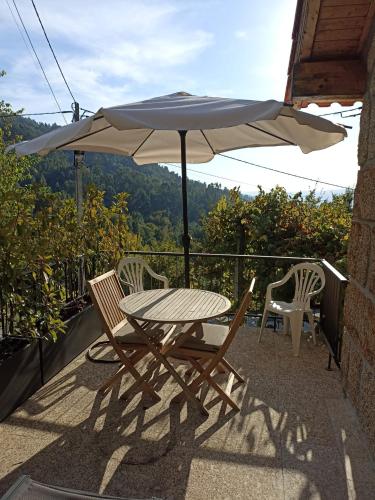 a table and two chairs and an umbrella on a balcony at Casa AURORA in Amarante