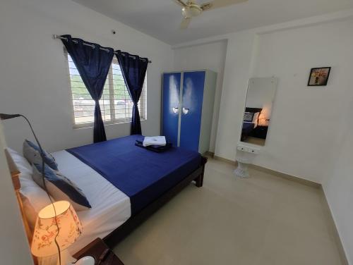 ein Schlafzimmer mit einem blauen Bett und einem Fenster in der Unterkunft NK Homes - Serviced Apartments in Hyderabad